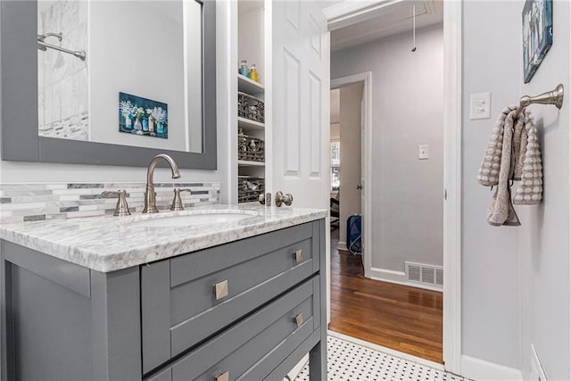 bathroom with visible vents, vanity, baseboards, and wood finished floors