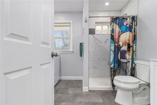 bathroom with toilet, a stall shower, and baseboards