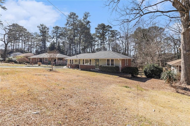 single story home with covered porch, brick siding, and a front yard