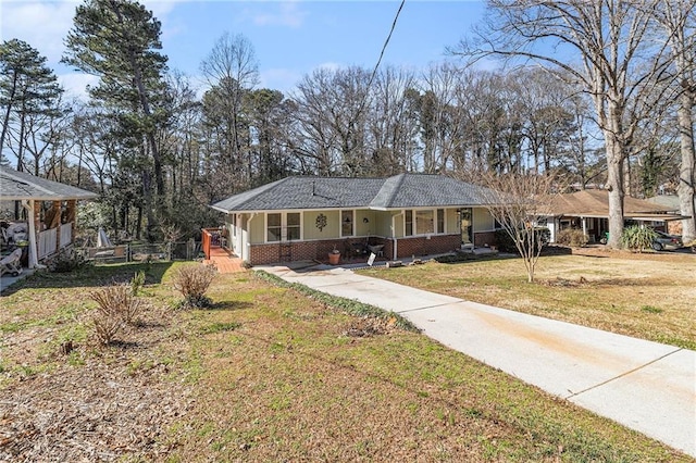 single story home with a porch, a front yard, concrete driveway, and brick siding