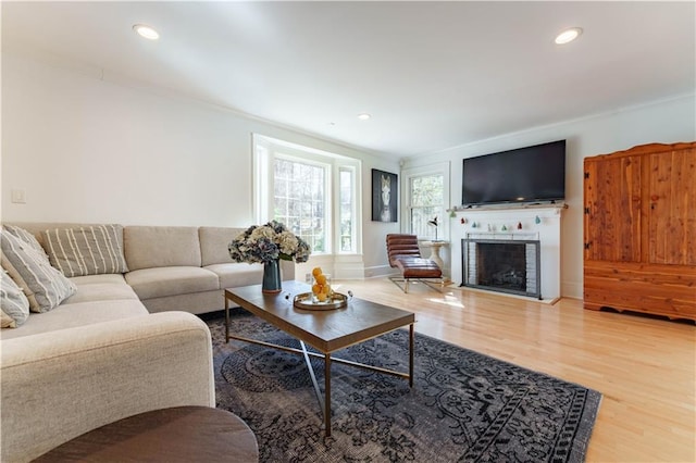 living area featuring a fireplace with flush hearth, recessed lighting, and wood finished floors