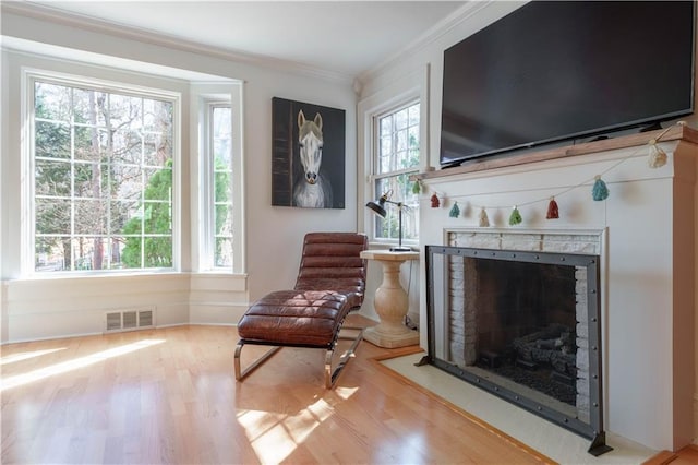 living area featuring a wealth of natural light, wood finished floors, visible vents, and crown molding