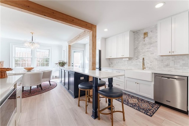 kitchen with decorative backsplash, dishwasher, beamed ceiling, light countertops, and a sink