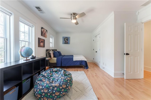 bedroom with ornamental molding, baseboards, visible vents, and light wood finished floors