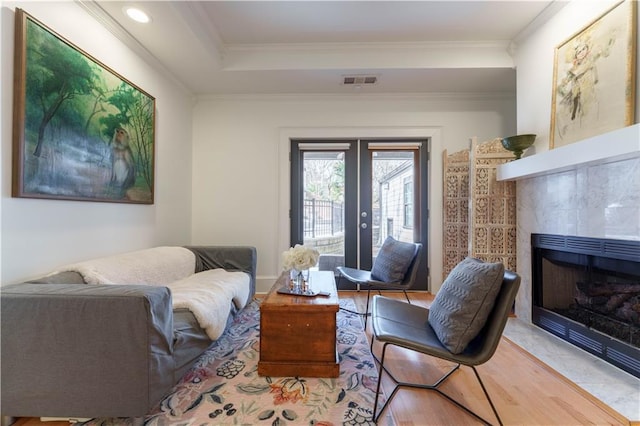 living area featuring a fireplace, visible vents, crown molding, and french doors