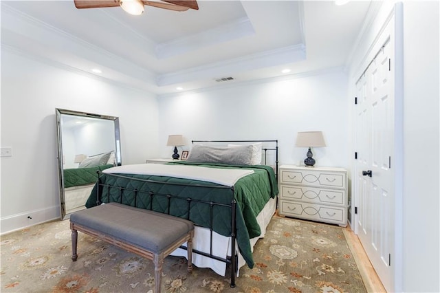 bedroom with crown molding, a raised ceiling, visible vents, a ceiling fan, and baseboards