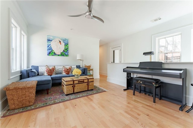 living room featuring a ceiling fan, baseboards, visible vents, and wood finished floors