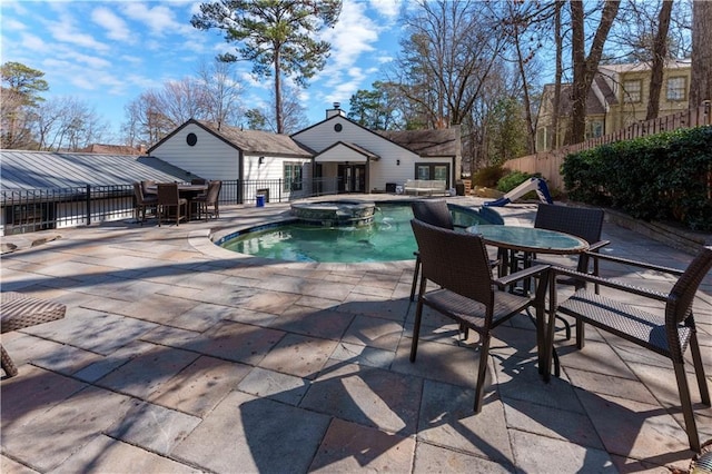 view of pool with outdoor dining space, a patio area, fence, and a pool with connected hot tub