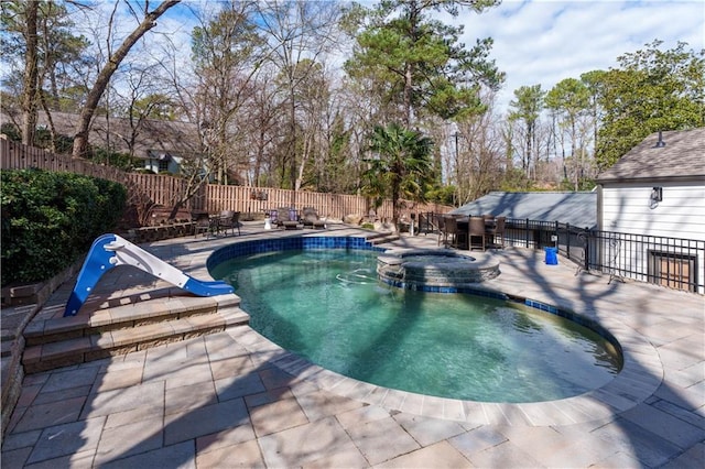 view of swimming pool with a pool with connected hot tub, a fenced backyard, a patio, and a water slide