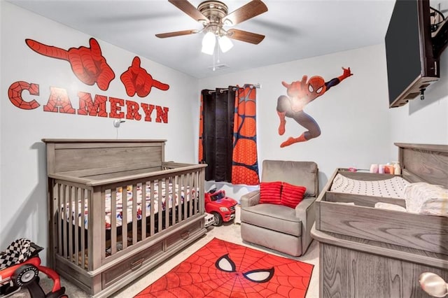 bedroom with a ceiling fan, carpet floors, a nursery area, and visible vents