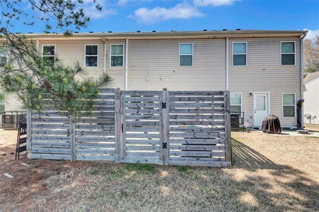 rear view of house featuring a gate, central AC, and fence