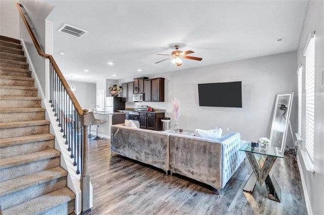 living area featuring stairway, recessed lighting, ceiling fan, visible vents, and wood finished floors