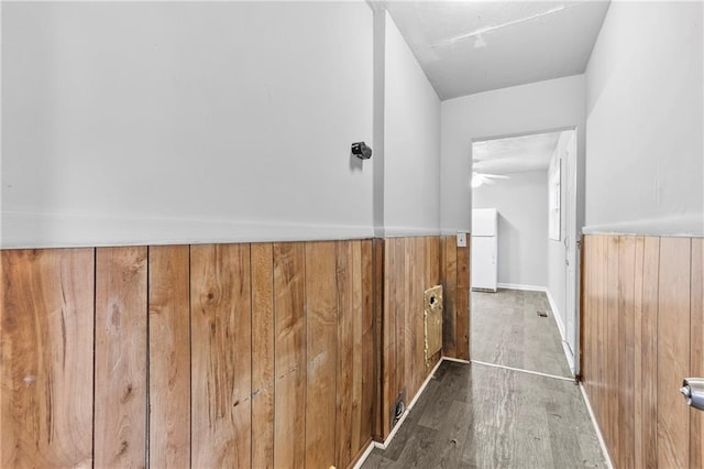 hall featuring dark wood-type flooring and wooden walls