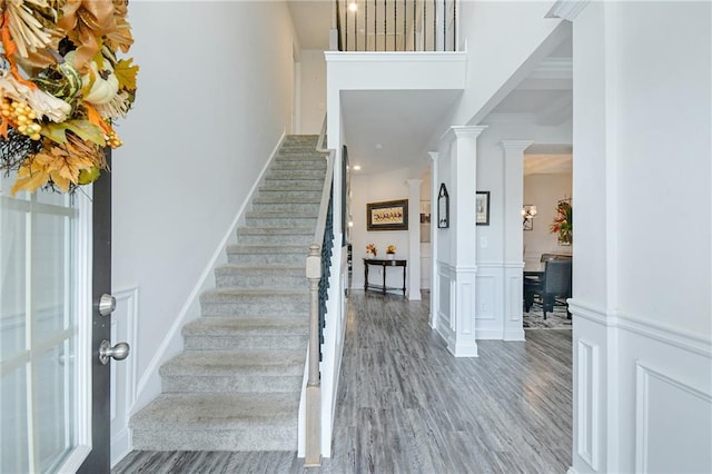 stairway with hardwood / wood-style flooring and decorative columns