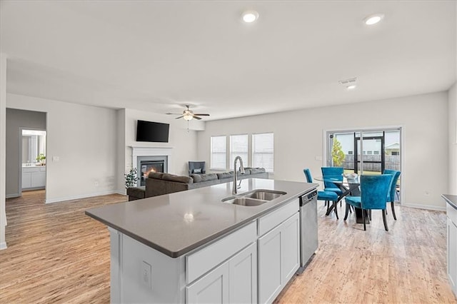 kitchen with white cabinetry, sink, a kitchen island with sink, ceiling fan, and stainless steel dishwasher