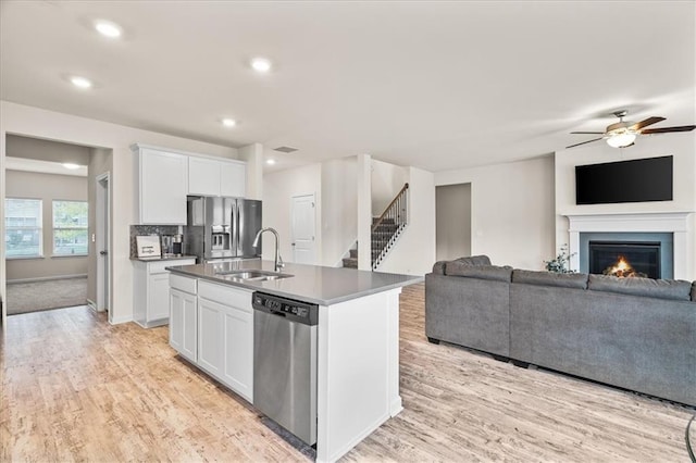 kitchen featuring sink, white cabinetry, appliances with stainless steel finishes, and a center island with sink