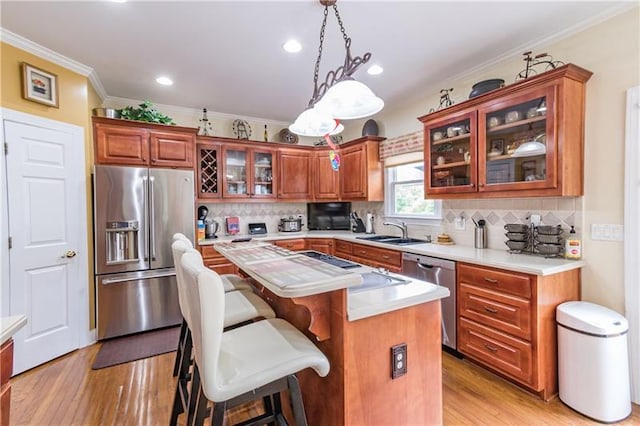 kitchen with decorative light fixtures, stainless steel appliances, a kitchen island, crown molding, and sink