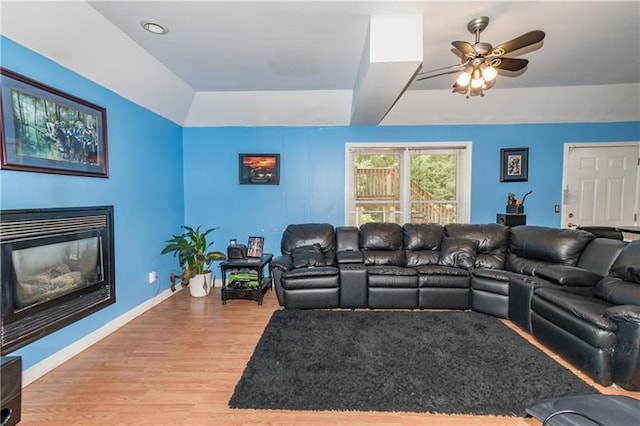 living room with wood-type flooring, a raised ceiling, and ceiling fan