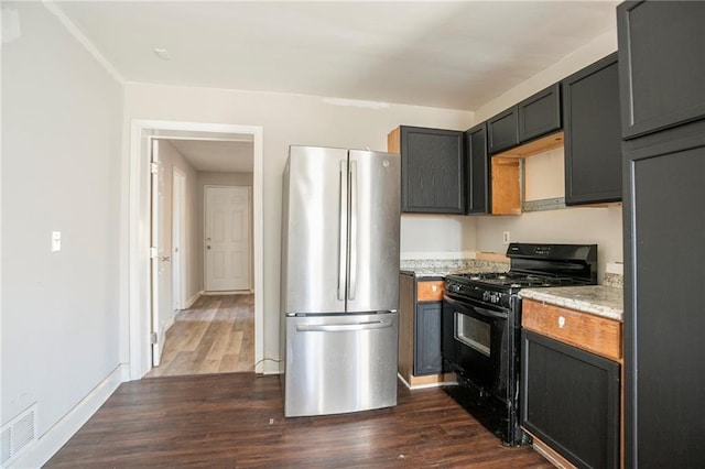 kitchen featuring dark wood-type flooring, black gas stove, baseboards, light countertops, and freestanding refrigerator