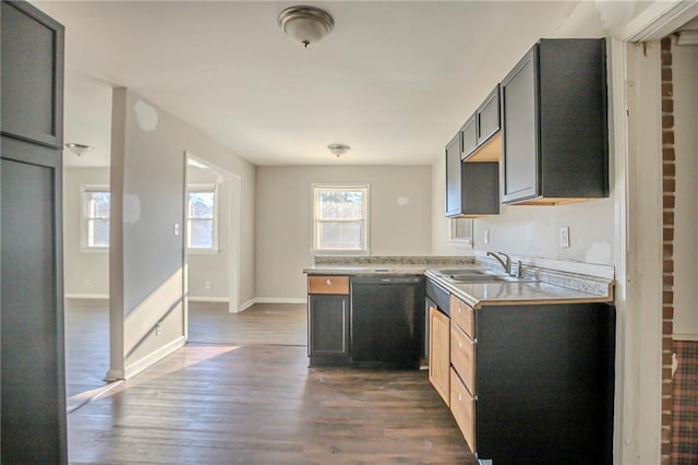 kitchen with light countertops, dark wood-type flooring, a sink, dishwasher, and baseboards