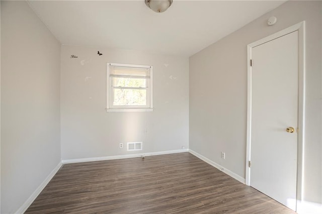 spare room featuring wood finished floors, visible vents, and baseboards