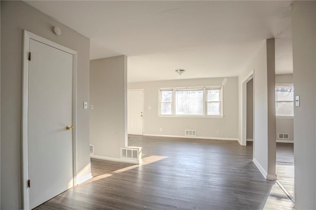 empty room featuring dark wood-style floors, visible vents, and baseboards