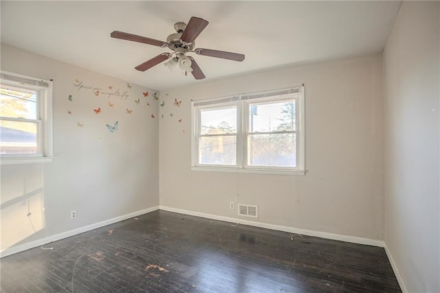 empty room featuring ceiling fan, wood finished floors, visible vents, and baseboards