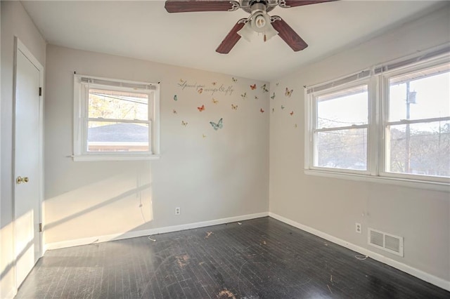 unfurnished room with visible vents, plenty of natural light, baseboards, and wood finished floors