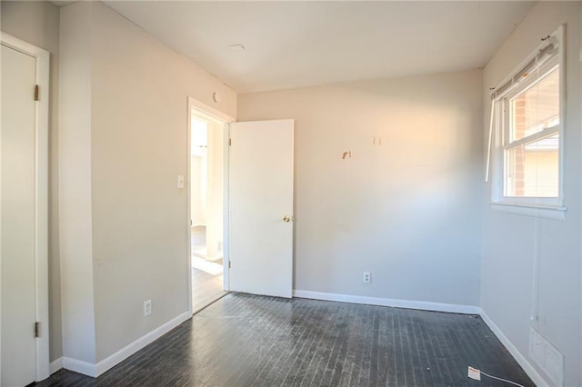 spare room featuring wood finished floors, visible vents, and baseboards