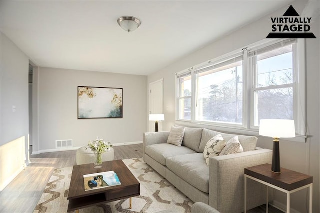 living room featuring wood finished floors, visible vents, and baseboards