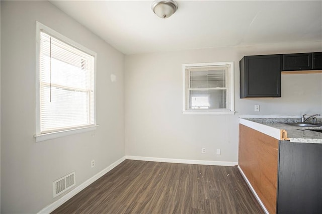 kitchen featuring dark wood-style floors, light countertops, visible vents, dark cabinets, and baseboards