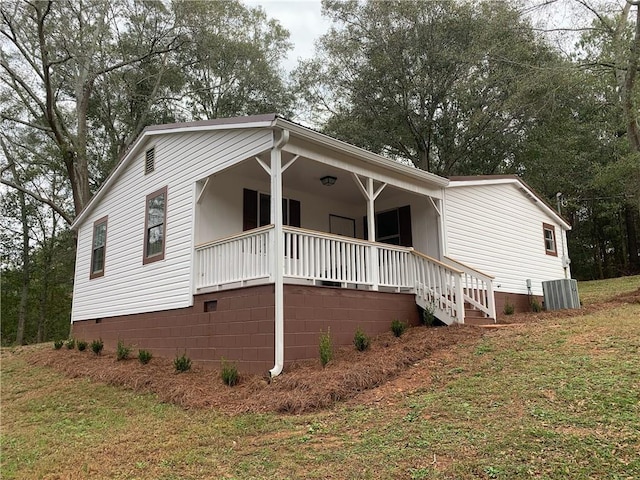 view of front facade featuring covered porch, central AC, and a front yard