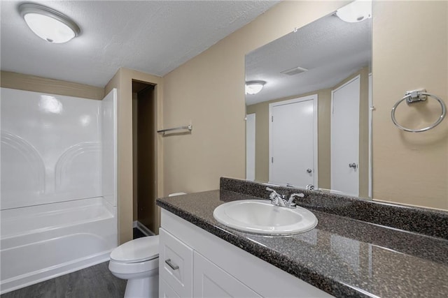 full bathroom with shower / bath combination, a textured ceiling, toilet, vanity, and hardwood / wood-style flooring