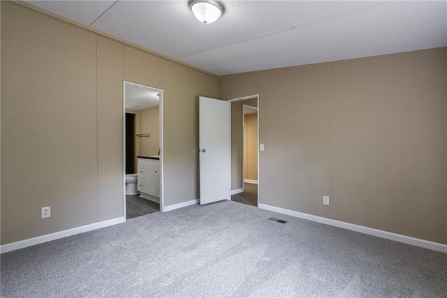 unfurnished bedroom with dark colored carpet and ensuite bath