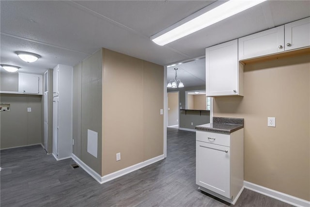 kitchen featuring decorative light fixtures, white cabinetry, dark wood-type flooring, and a notable chandelier