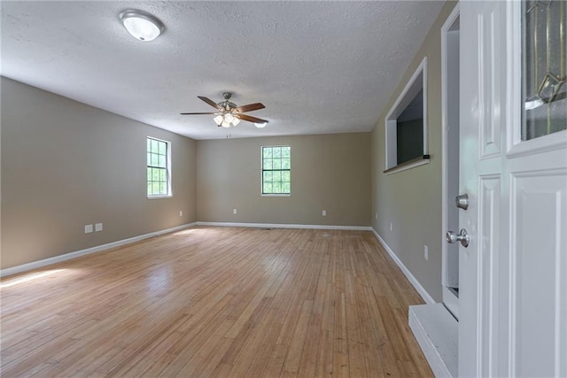 empty room featuring a textured ceiling, light wood-type flooring, and ceiling fan