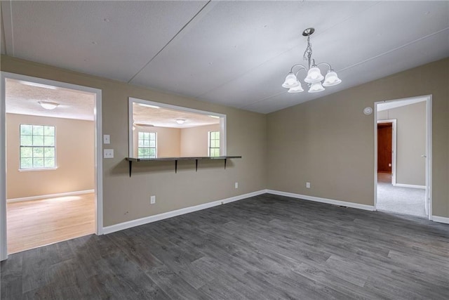 spare room featuring a wealth of natural light, dark hardwood / wood-style flooring, and a notable chandelier