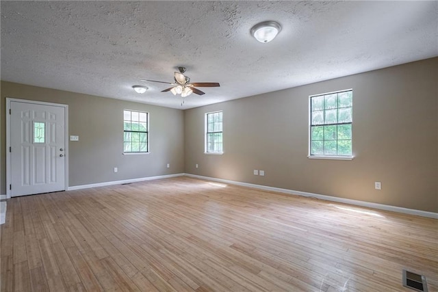 spare room featuring ceiling fan, light wood-type flooring, and a textured ceiling