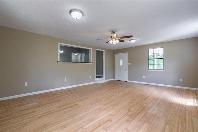 empty room with ceiling fan, light hardwood / wood-style floors, and a textured ceiling