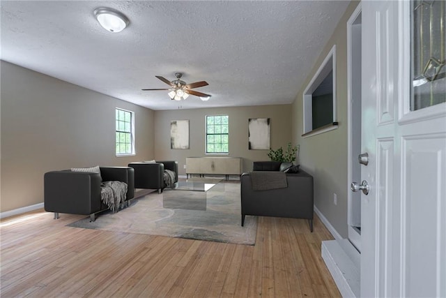 living room with ceiling fan, light hardwood / wood-style flooring, and a textured ceiling