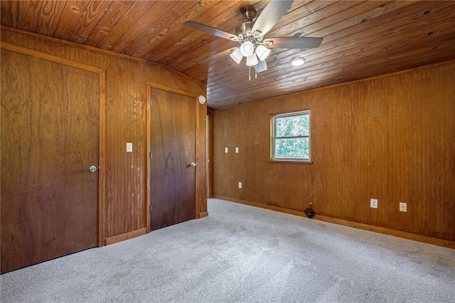 unfurnished bedroom featuring carpet, ceiling fan, wood walls, and wooden ceiling