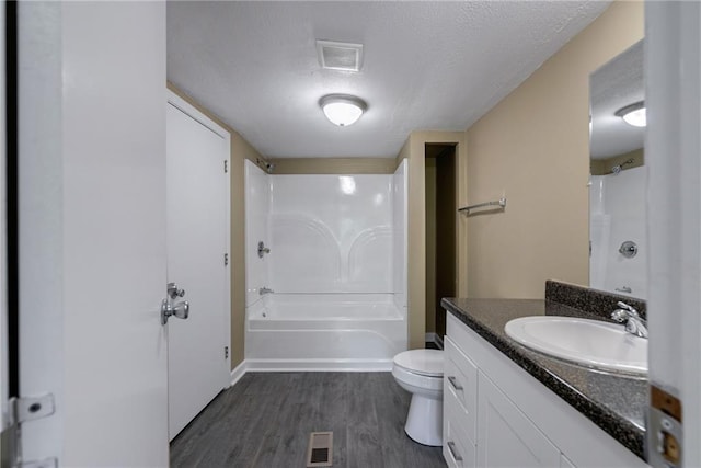 full bathroom featuring hardwood / wood-style floors, a textured ceiling, toilet, shower / washtub combination, and vanity