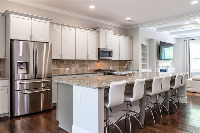 kitchen featuring light stone countertops, sink, stainless steel appliances, and an island with sink