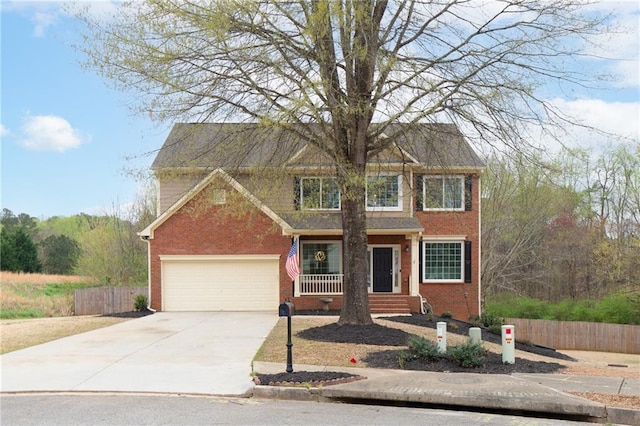 traditional-style house with concrete driveway, brick siding, and fence