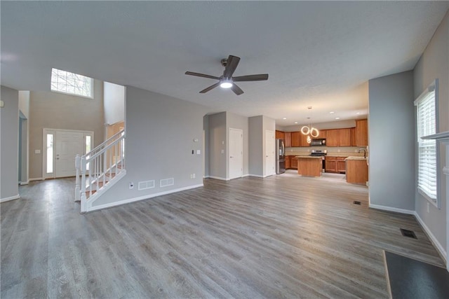 unfurnished living room with visible vents, baseboards, and stairs