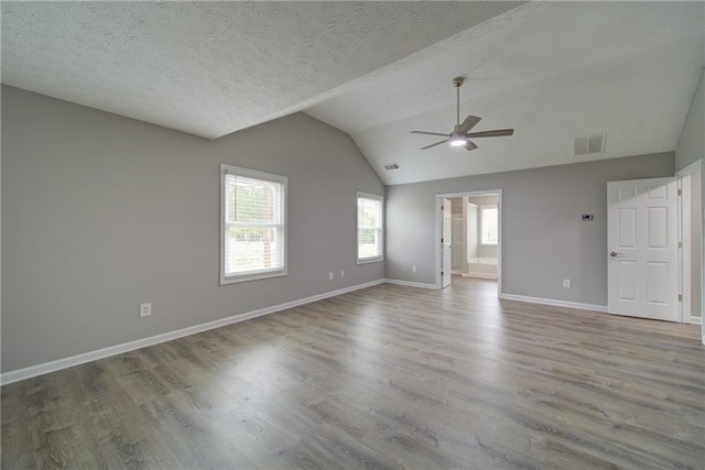 unfurnished living room with vaulted ceiling, a ceiling fan, wood finished floors, baseboards, and visible vents