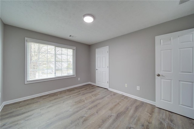 unfurnished bedroom featuring wood finished floors, visible vents, and baseboards