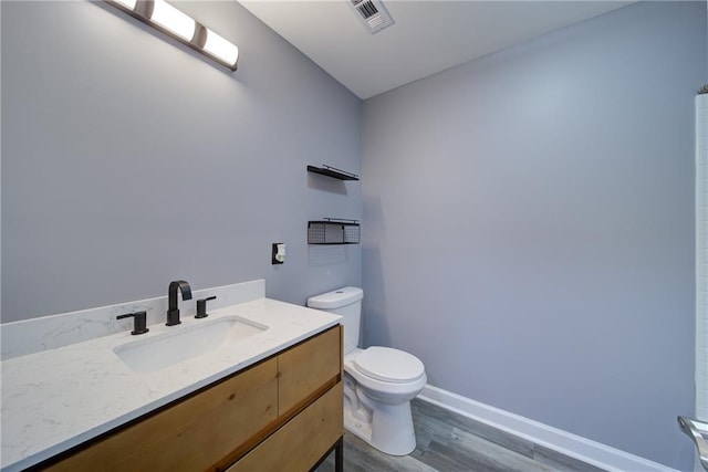 bathroom featuring wood finished floors, visible vents, toilet, vanity, and baseboards
