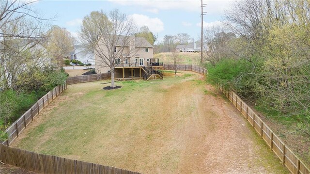 view of yard with a fenced backyard, a wooden deck, and stairway