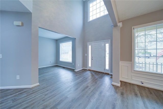 entrance foyer with baseboards, a towering ceiling, and wood finished floors